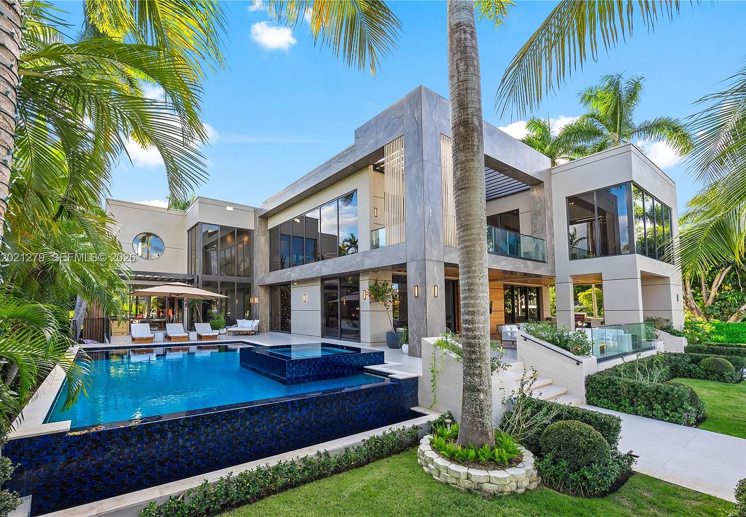 Infinity pool meeting the bay at the rear elevation, mature palms framing the upper terrace
