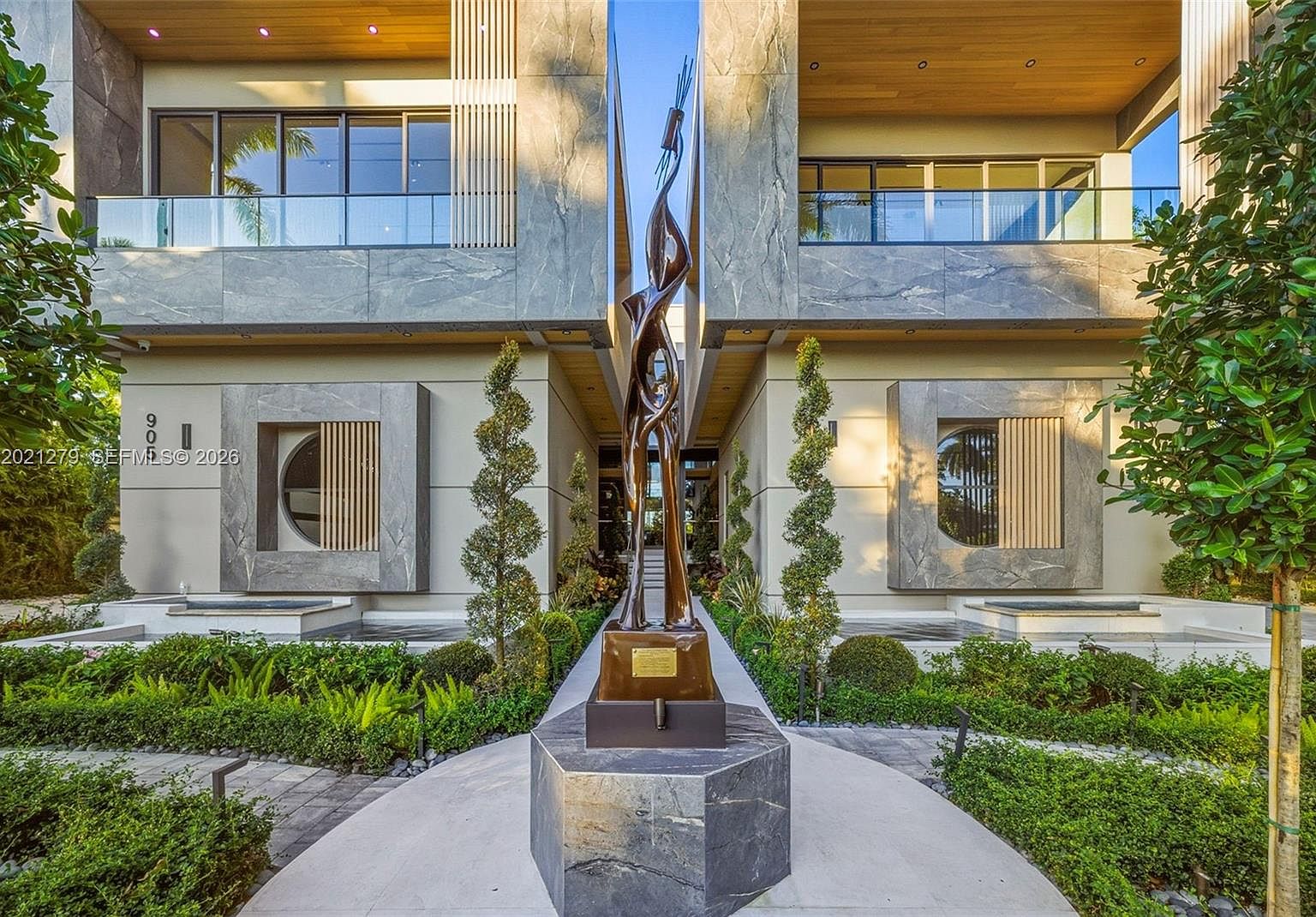 The bronze sculpture at the entry pavilion, framed by stone walls and a covered walkway